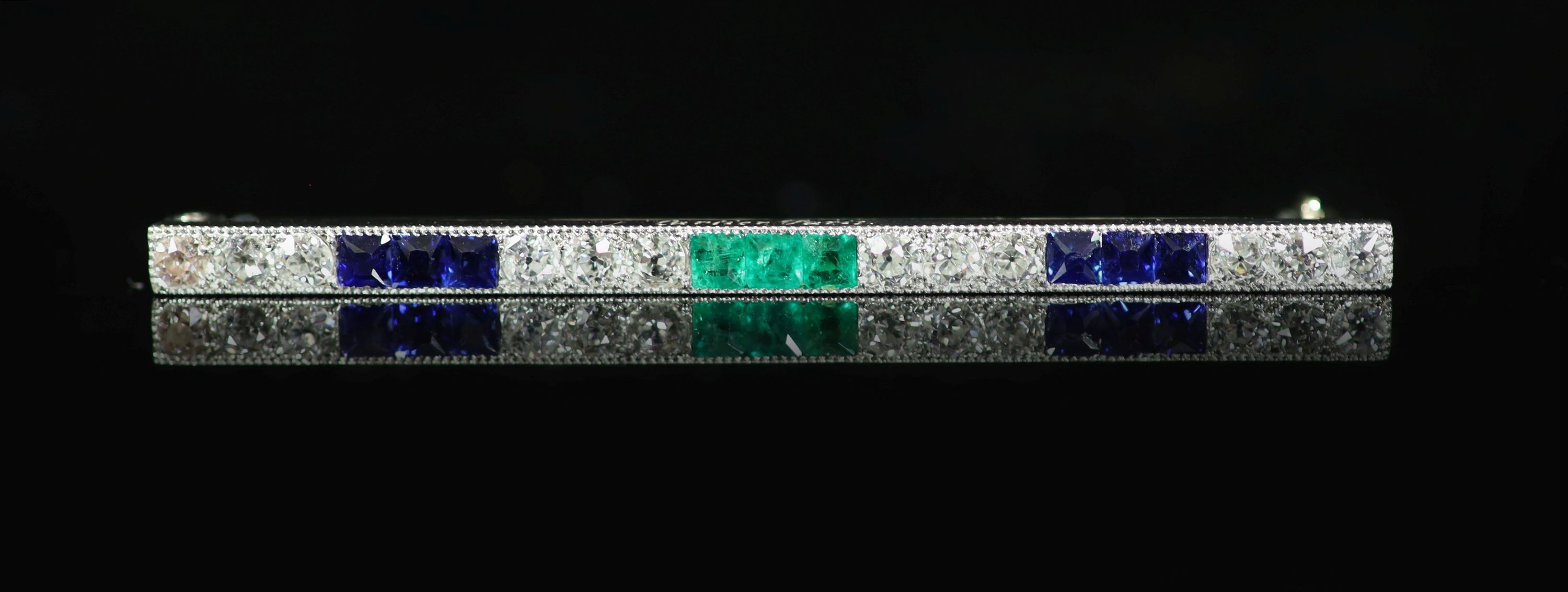 A mid 20th century Cartier platinum, twelve stone diamond, six stone sapphire and three stone emerald miilegrain set bar brooch